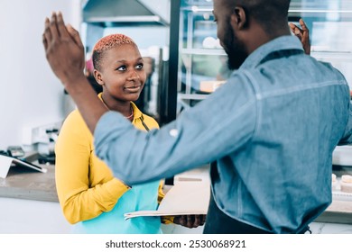 African American man gesturing with hands and telling interesting story to female colleague while standing near cafe counter during break together - Powered by Shutterstock