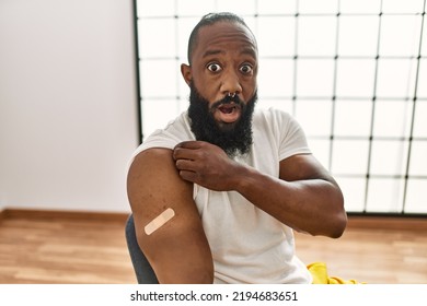 African American Man Getting Vaccine Showing Arm With Band Aid Scared And Amazed With Open Mouth For Surprise, Disbelief Face 