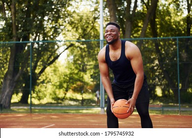 African American Man With Girl Plays Basketball On The Court Outdoors.