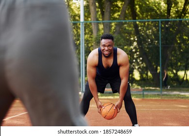 African American Man With Girl Plays Basketball On The Court Outdoors.