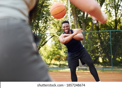 African American Man With Girl Plays Basketball On The Court Outdoors.