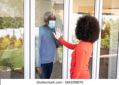 African American man greeting his adult daughter through window door, wearing face mask. Social distancing and self isolating at home during Coronavirus Covid 19 quarantine lockdown. - Powered by Shutterstock