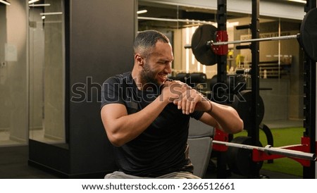 African American man guy in gym doing sport exercise with dumb-bells workout sportsman athlete lifting up heavy dumbbells weights feel sharp pain in shoulder hand painful injury trauma ache stretching