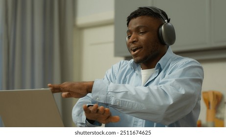 African American man happy singing dancing ethnic guy biracial male in headphones listen to music at kitchen home laptop having fun moving hands to musical audio song joy dance sing enjoy earphones - Powered by Shutterstock