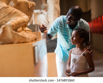 African American man and his little daughter looking at exhibits of antique sculpture at historical museum