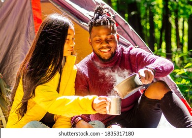 African American Man And Hispanic Woman Drinking Tea , Cooking Food On A Gas-burner