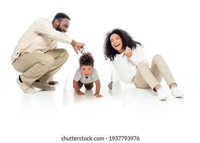 African American Man Holding Paper Roof Above Crawling Son Near Laughing Wife On White