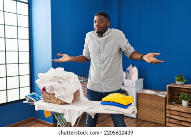 African american man ironing clothes at home shouting and screaming loud to side with hand on mouth. communication concept.  - Powered by Shutterstock