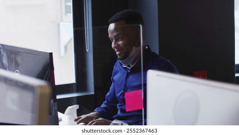 African american man with lowered face mask using computer at modern office. social distancing quarantine lockdown during coronavirus pandemic - Powered by Shutterstock