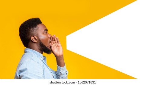 African american man making loud announcement at copy space, holding hand near his open mouth over yellow background, side view - Shutterstock ID 1562071831
