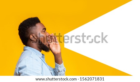 African american man making loud announcement at copy space, holding hand near his open mouth over yellow background, side view