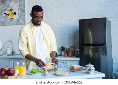 African American Man Making Sandwich With Cheese And Lettuce In Kitchen