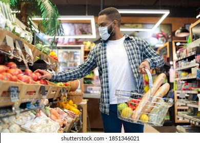 African American Man In Mask Doing Grocery Shopping Buying Vegetables And Fruits In Supermarket, Walking With Basket Full Of Food In Store. Male Customer In Groceries Shop Concept