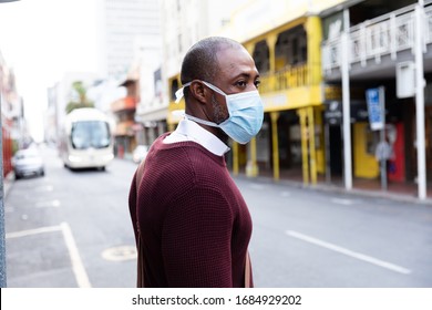 African American man out and about in the city streets during the day, wearing a face mask against air pollution and covid19 coronavirus, crossing the street. - Powered by Shutterstock