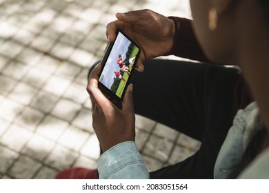 African american man in park watching rugby match on smartphone. sports, competition, entertainment and technology concept digital composite image. - Powered by Shutterstock