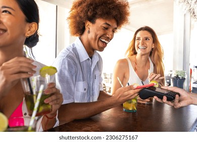 African American man paying at beach bar with phone. Black male paying round of drinks with mobile phone on vacation. - Powered by Shutterstock