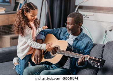 African American Man Playing Guitar With His Cute Daughter