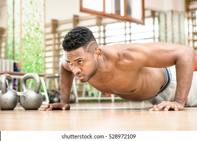 African American Man Push Up Chest Exercise And Gritty Serious Facial Expression Inside Gym - Attractive Black Guy Shirtless Body Training Muscles On The Floor - Concept Of Sports And Fitness Indoor