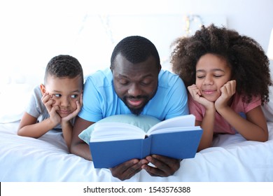 African American man reading bedtime story to his children on bed - Shutterstock ID 1543576388