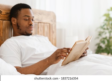 African American Man Reading Books Enjoying Weekend Morning Sitting In Bed In Bedroom At Home, Focus On Book. Read More Concept. Selective Focus, Shallow Depth