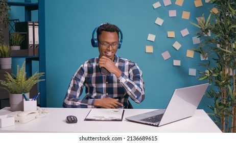 African american man recording and singing song on smartphone with audio headset. Happy adult listening to mp3 music and doing karaoke session, using mobile phone as microphone.