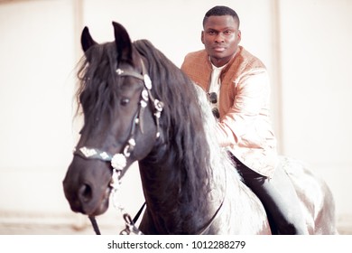 african american man riding black horse in hangar - Powered by Shutterstock