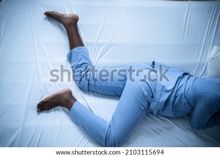 African American Man With RLS - Restless Legs Syndrome. Sleeping In Bed