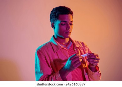 african american man rolling cigarette for smoking on colorful background with blue neon lighting - Powered by Shutterstock