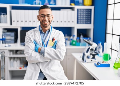 African american man scientist smiling confident sitting with arms crossed gesture at laboratory - Powered by Shutterstock