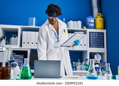 African American Man Scientist Using Laptop Holding Clipboard At Laboratory