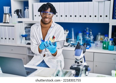 African American Man Scientist Using Laptop Writing On Clipboard At Laboratory