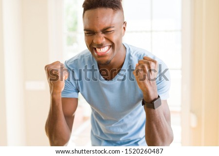 Similar – Cheerful man celebrating his success with a broad smile and raised fist in front of a neutral background