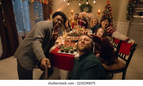 African American man with selfie stick takes family group photo. Multi cultural family celebrating Christmas or New Year 2023. Atmosphere of family Christmas dinner at home. Camera view. - Powered by Shutterstock