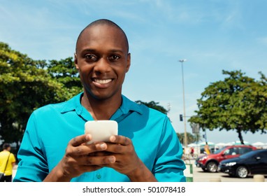 African American Man Sending Message With Phone Outdoor In The City In A Warm Cinema Look