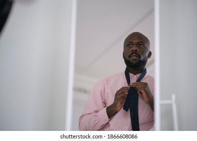 African American man in shirt dressing up and adjusting tie on neck at home. - Powered by Shutterstock