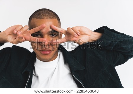 African American man showing V sign with both hands over his eyes on a white studio background. High quality photo