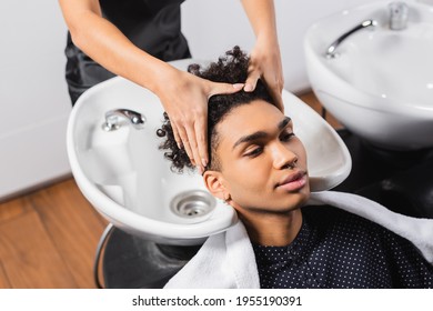 African American Man Sitting Near Hairdresser Washing Hair And Sink On Blurred Background