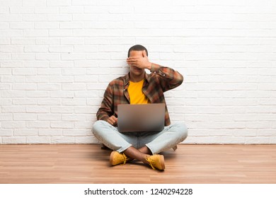 African american man sitting on the floor with his laptop covering eyes by hands. Do not want to see something - Shutterstock ID 1240294228
