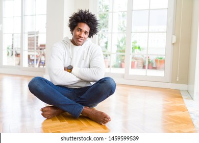 African American man sitting on the floor at home happy face smiling with crossed arms looking at the camera. Positive person.