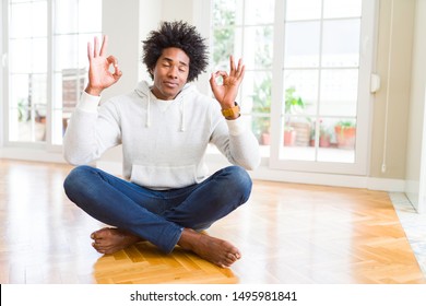 African American man sitting on the floor at home relax and smiling with eyes closed doing meditation gesture with fingers. Yoga concept.