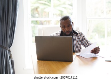 African American Man Sitting At Table In Dining Room, Working Remotely Using Laptop. Flexible Working From Home With Technology.