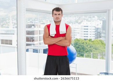 African American man standing next to large windows in fitness studio with towel and exercise ball. Sport, wellness, modern, active, motivation, healthy, urban