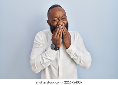 African American Man Standing Over Blue Background Laughing And Embarrassed Giggle Covering Mouth With Hands, Gossip And Scandal Concept 