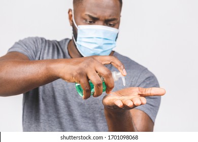 African american man in sterile face mask isolated on white background. Epidemic pandemic coronavirus 2019-ncov sars covid-19 flu virus concept. Holding bottle with antibacterial sanitizer. - Powered by Shutterstock