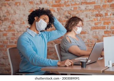 African American Man Stretching Neck In Workstation 
