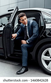 African American Man In Suit Opening Black Car Door