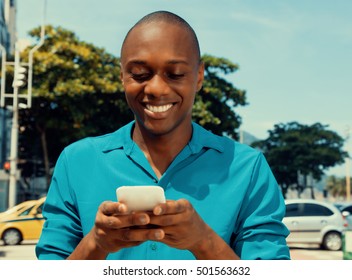 African American Man Surfing The Internet By Phone Outdoor In The City In A Warm Cinema Look