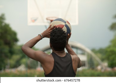 African american man throw ball on basketball court to target, back view