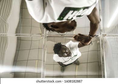 african american  man touching his reflection in the mirror ceiling. black male standing in narrow long corridor