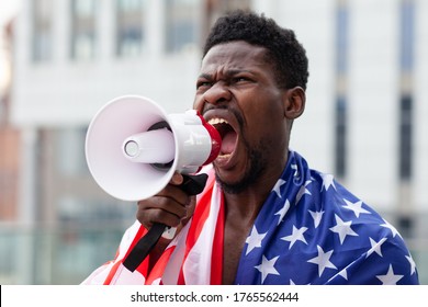 African American Man With Usa Flag Protests And Shouts Into A Megaphone Shows Aggression On White, Activist Guy On Strike, Black Lives Matters Concept, Close-up